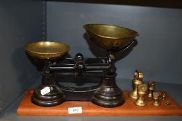 A cast kitchen balance scale set having brass pans and weight set