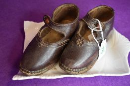 A pair of antique child shoes or clogs with leather body and wooden sole with wood worm