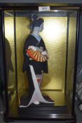 A cased ceramic figure of a Geisha by Hakata being hand decorated