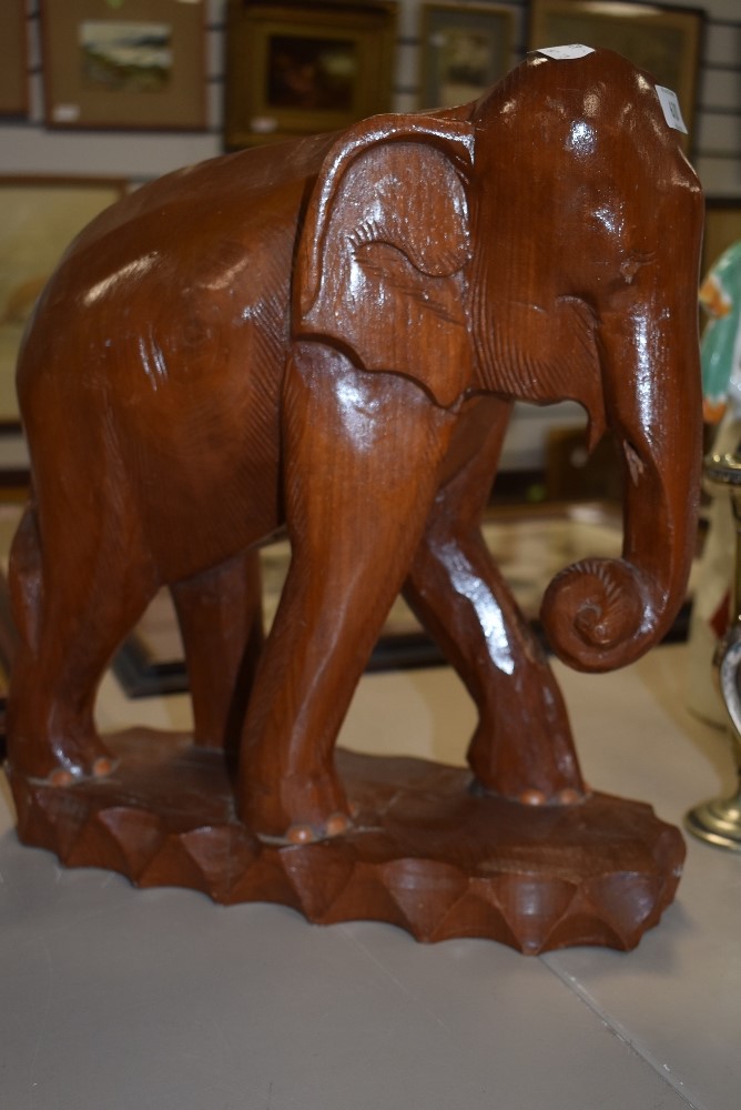 A large hand carved wooden figure of an African elephant standing 36cm high