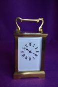 A French brass cased carriage clock having visible escape and bevel edged panels with enamel face