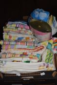 A box full of colourful vintage towels and tea towels, some still having original packaging.