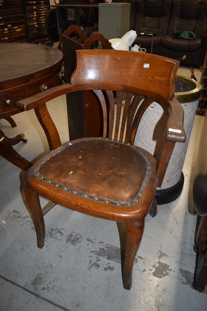 An Edwardian captains or office arm chair having oak frame with leather button seat