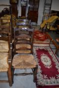 Three 19th Century oak ladder back chairs having rush seats