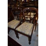 A pair of Victorian balloon and carved back dining chairs with mahogany frames