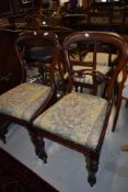 A pair of Victorian balloon and carved back dining chairs with mahogany frames