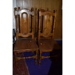 A set of four traditional oak colonial style dining chairs having panel backs and solid seats