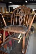 A childs low rocking arm chair in dark stain by Ercol having blue badge