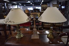 Two brass bodied table lamps and a candle stem