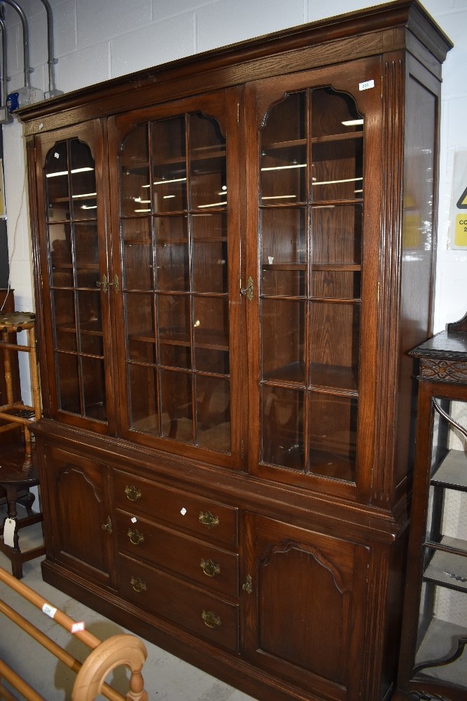 A reproduction oak bookcase, of nice quality having glazed top over drawer and cupboard base,