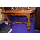 An early 20th Century oak drawer leaf dining table of interesting design having rounded top and