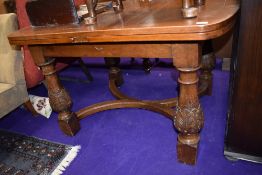 An early 20th Century oak drawer leaf dining table of interesting design having rounded top and