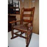 A childs oak framed rocking chair with woven fibre seat and ladder style back