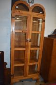 A modern light pine glass fronted display cupboard with wrought iron fitments