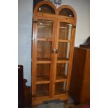 A modern light pine glass fronted display cupboard with wrought iron fitments