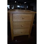 A modern golden oak effect three drawer chest