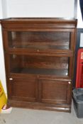 An early 20th Century oak stacking bookcase, in the Globe Wernicke style, having cupboard base