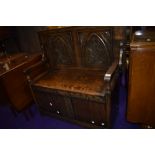 An early 20th Century oak monks bench, having carved gothic style panel top
