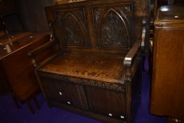 An early 20th Century oak monks bench, having carved gothic style panel top