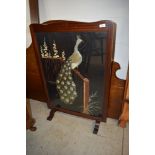 A Victorian mahogany framed ire screen having peacock needle work decoration front