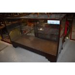 A vintage stained frame and glazed shop counter having sliding doors, width approx 137cm, some