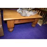 A light stained coffee table, on heavy legs