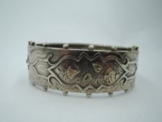 A Victorian silver hinged bangle having engraved and applique gold decoration and beaded rim, approx