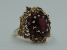 A garnet cluster dress ring in a claw set raised moulded mount on a 9ct gold loop, size M & 4.6g