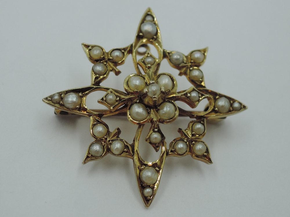 An Edwardian yellow metal brooch stamped 9ct in an open star form having seed pearl decoration,