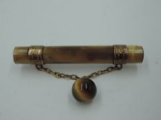 A vintage tigers eye bar brooch having yellow metal bands with chain connecter to tigers eye bead