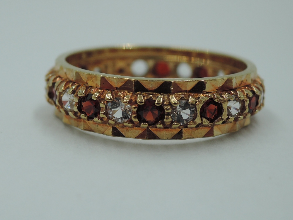 A 9ct gold full eternity ring set with garnet and cubic zirconia in a cut mount, size P & 3.7g