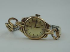 A lady's vintage 9ct gold Omega wrist watch having a baton numeral dial to champagne face in a 9ct