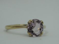 An amethyst solitaire ring having a four double claw set mount on a yellow metal loop stamped 9ct,