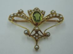 An Edwardian yellow metal brooch having a central peridot with seed pearl decoration, (1 pearl