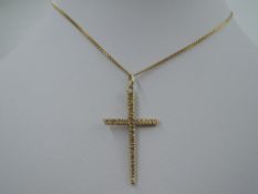 A 9ct gold cross with bark effect decoration on a gold plated chain
