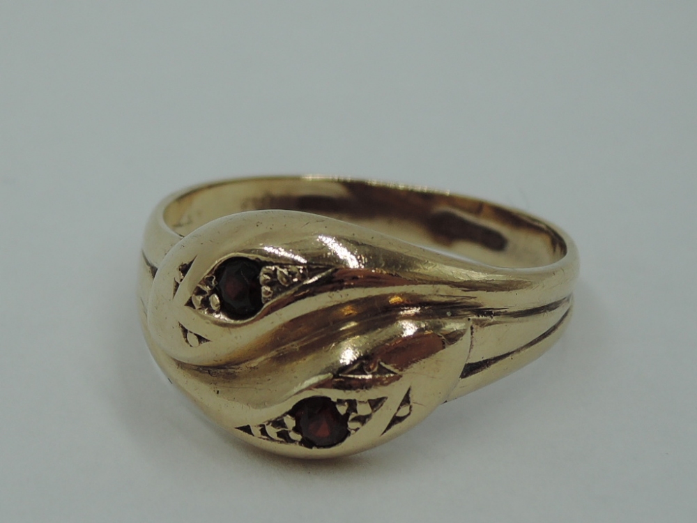 A 9ct gold entwined snake ring having inset garnet eyes, size V & approx 4.3g