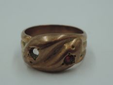 A 9ct rose gold entwined snake ring having ruby set eyes (one missing), size R & approx 7.1g