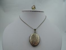 A silver locket having engraved floral decoration and a white metal dress ring having large oval