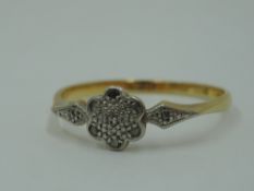 A small diamond chip cluster ring in an illusionary pave mount on a yellow metal loop stamped