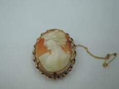 A conch shell cameo brooch depicting a maiden in profile in a 9ct gold mount with twist
