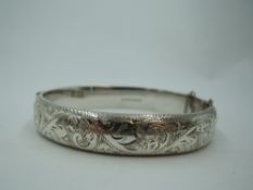 A silver hinged bangle having engraved scroll decoration, approx 20.2g