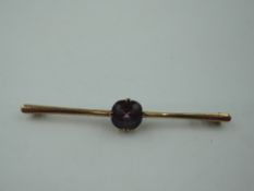 A yellow metal bar brooch stamped 9ct having central facetted amethyst, approx 3.9g