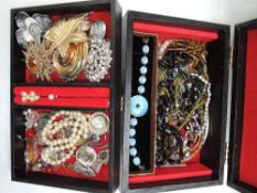 A small jewllery case containing a selection of costume jewellery including earrings, brooches and