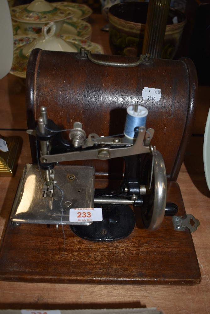 A small size hand cranked childs or similar sewing machine by ALL having wooden case