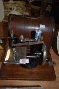 A small size hand cranked childs or similar sewing machine by ALL having wooden case