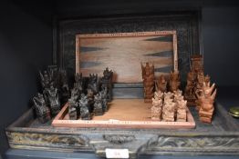 A part chess set being hand carved with an Indonesian design and similar carved and decorated