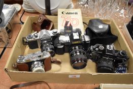 Four cameras including a Canon T70 with instruction book, a Praktica BC1, a Halina 35X and a