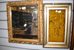 A gilt and gesso framed hall way mirror and ceramic relief wall tile of priest and parson smoking