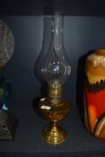 A brass bodied oil burning lamp with amber glass well made by Gladiator