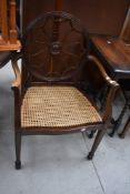 An early 20th Century cane seated carver chair of interesting design having wheel style back